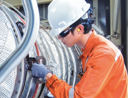 Person wearing hard hat working at large machine part