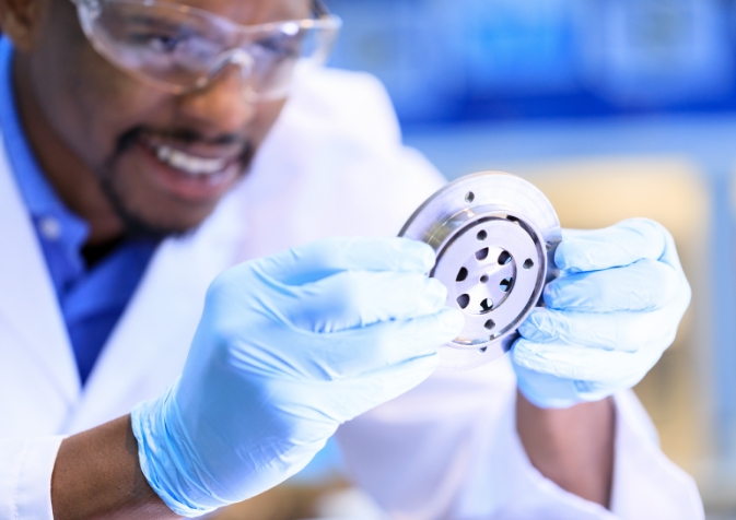 Person with rubber gloves with small machine part