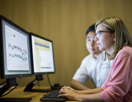 Two people looking at two screens