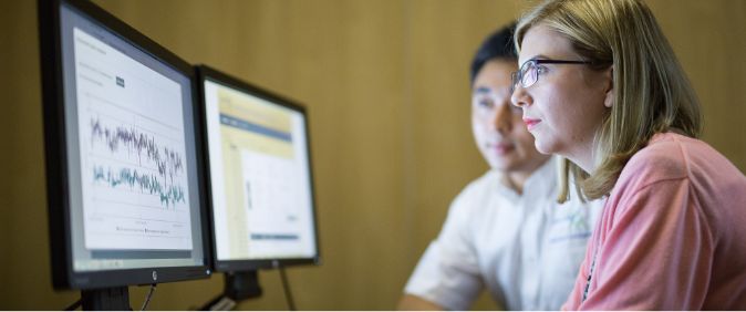 Two people looking at two screens